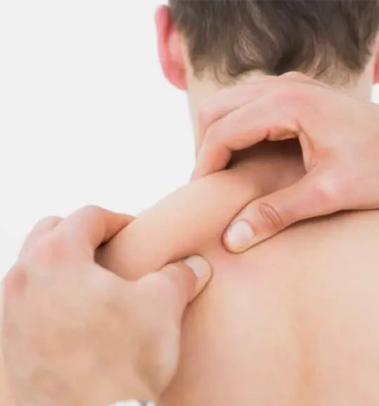 Person receiving a massage on the upper back and neck area.