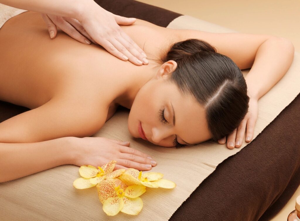 Woman at spa receiving back massage with orchids