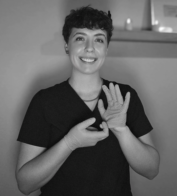 Smiling woman wearing gloves in black scrubs.