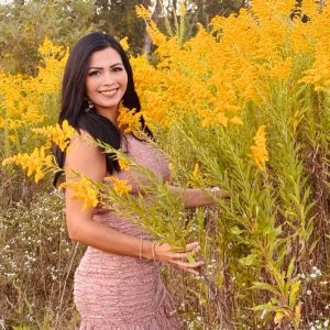 Woman in pink dress surrounded by tall yellow flowers.
